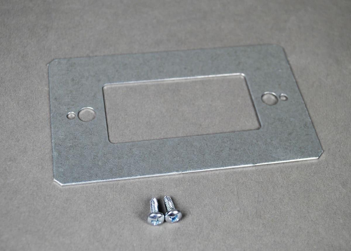 Here's an alt tag for the image: Metal wall plate and screws.