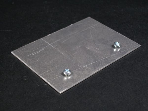 Here's an alt tag for the image: Metal plate with two screws.