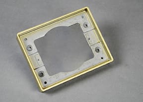 Gold-colored metal electrical outlet mounting plate.